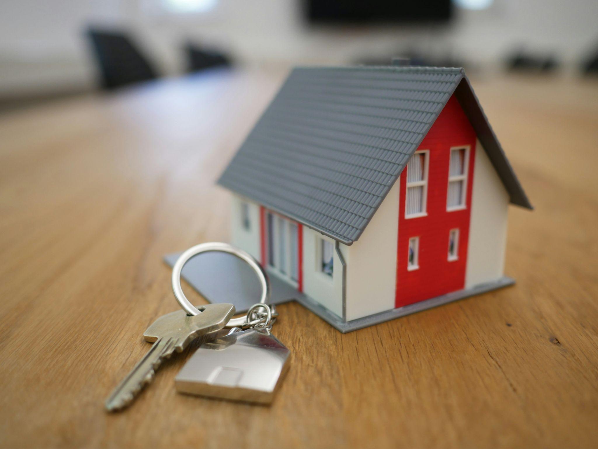 House model with keys on a table representing property purchase, mortgage planning, and real estate investment